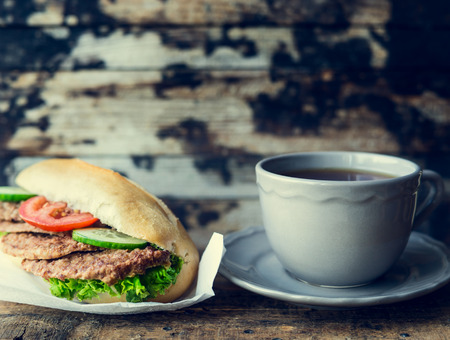 cup of tea and a sandwich with meat on a dark wooden background , tonedの写真素材