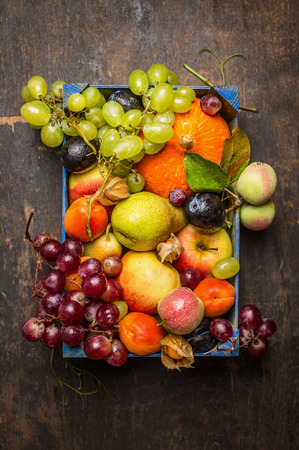 various fresh sharvest fruits in a blue box on a dark wooden texture, top viewの写真素材