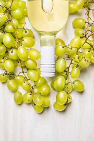 bottle of white wine and ripe grapes on rustic white wooden background, top viewの写真素材