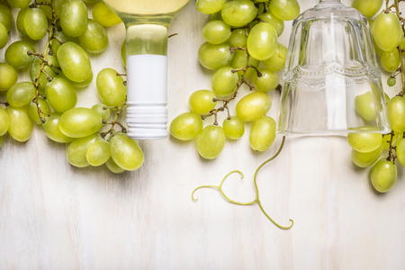 bright grapes with a bottle of white wine and glass on rustic  a white wooden backgroundの写真素材