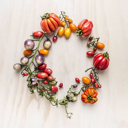 fresh colorful tomatoes on branches with leaves, lined circle on a wooden background, top viewの写真素材