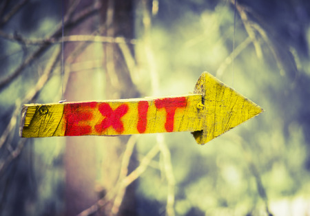 yellow wooden plaque in the form of an arrow with the word "exit"  in climbing forest or high wire park on nature sunny background, close upの写真素材