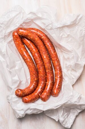long sausage meat in white wrapping paper on wooden  background, top viewの写真素材