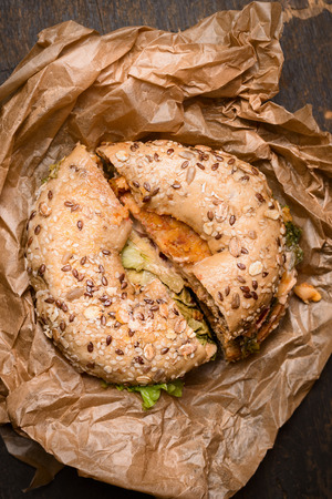 Sandwich on a Bagel with chiken and salad leaves and Cheese on rustic wooden background, close up, top viewの写真素材