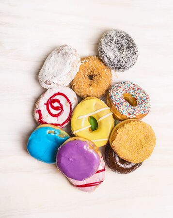 heap of colorful donuts on white wooden background, top viewの写真素材