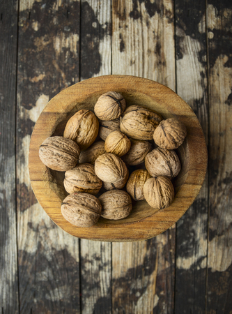 walnuts in a wooden bowl on wooden rustic background, top viewの写真素材