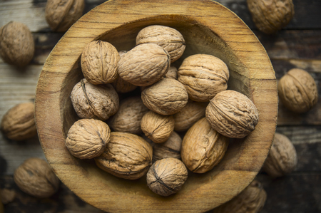 walnuts in a wooden bowl on a rustic wooden background, top view, close upの写真素材