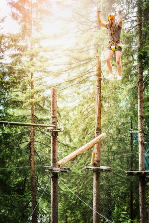 Young guy is climbing on the rope in climbing forest on nature bakgrundの写真素材