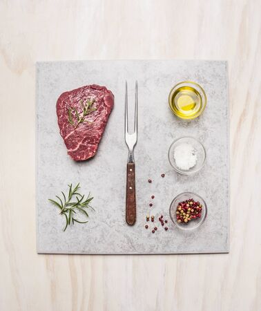 Raw fresh meat Steak with spice ingredients on light marble plate over wooden background, top viewの写真素材