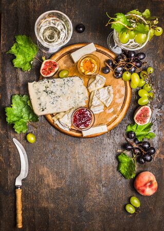 cheese snack Gorgonzola and Camembert with wine glass honey knife cheese grapes on a branch with leaves Peaches on wooden rustic background top viewの写真素材