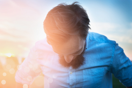 man in a shirt with a beard is tilting her head on sunny natural  background close upの写真素材