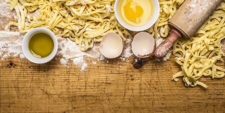 cooking pasta with eggs, flour, olive oil, rolling pin  on wooden rustic background top view close upの写真素材