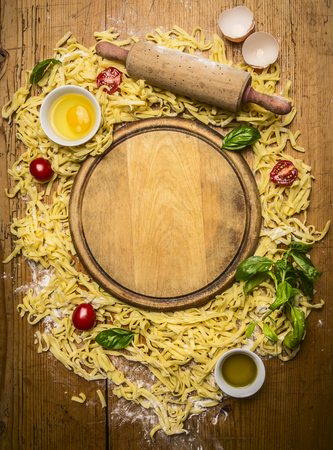 ingredients for making pasta, Flour, eggs, rolling pin, herb,olive oil, around cutting board on wooden rustic background top viewの写真素材