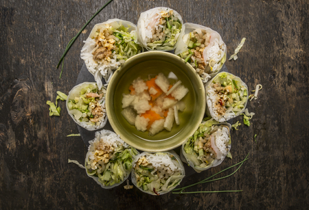 sliced rice rolls with a transparent noodle inside lined circle with vegetable soup on wooden background top viewの写真素材