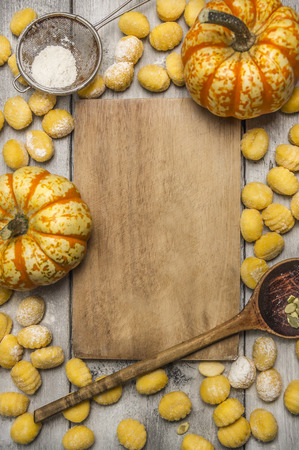 Ingredients for cooking pumpkin gnocchi  flour sieve flour wooden spoon almonds pumpkin, wooden cutting board on wooden rustic background top viewの写真素材