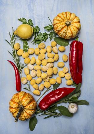 autumn vegetable pumpkin pepper lemon herbs garlic and pumpkin gnocchi on blue wooden background top viewの写真素材