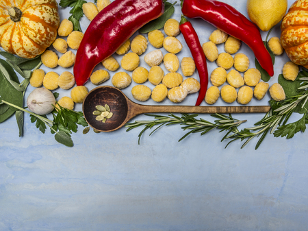 pumpkin gnocchi with wooden spoon and autumn fruits vegetables and herbs on blue wooden background top viewの写真素材