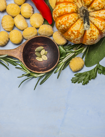 pumpkin gnocchi with wooden spoon almonds red pepper pumpkin rosemary on blue wooden background top view close upの写真素材