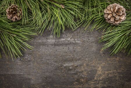 Christmas pine branches with cones on on wooden rustic background top viewの写真素材