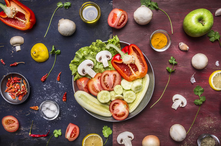concept cooking vegetarian food sliced cucumbers, tomatoes, onions mushrooms lettuce cucumbers apples in a pan with spices and herbs on wooden rustic background top view close upの写真素材