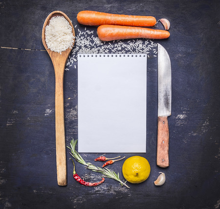 ingredients for cooking rice with vegetables, a knife, a wooden spoon, lemon, spicy, pepper, garlic lined frame with  sheet of paper text area on wooden rustic background top view close upの写真素材