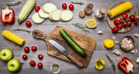 cutting board, lay around the cucumbers, peppers, tomatoes on a branch, lemon, corn, zucchini, apples, butter, spices and herbs, Healthy foods, cooking and vegetarian concept.の写真素材