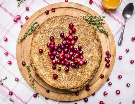 delicious pancakes on a cutting board with cranberries and honey, on a napkin on wooden rustic background top view close upの写真素材