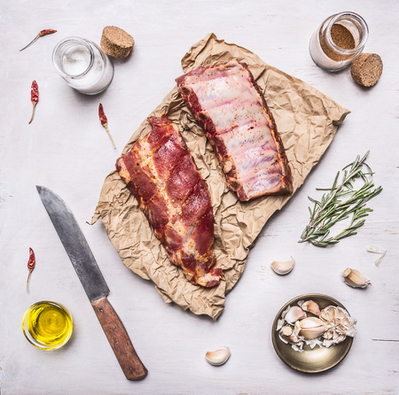 Ingredients for cooking double  raw lamb ribs on paper with a knife, garlic, salt, butter and herbs on white wooden rustic background top viewの写真素材