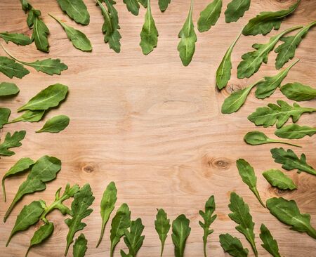 arugula leaves lined frame on wooden rustic background top view place for text, on wooden rustic background top viewの写真素材