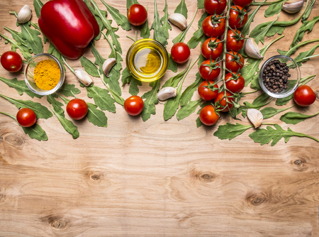 horizontal border with vegetables , oil, cherry tomatoes on a branch, pepper, seasoning, arugula, garlic border ,with text area on wooden rustic background top viewの写真素材