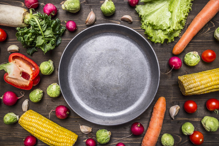 concept cooking vegetarian food ingredients laid out around the pan with a knife and spices space for text on rustic wooden background top viewの写真素材