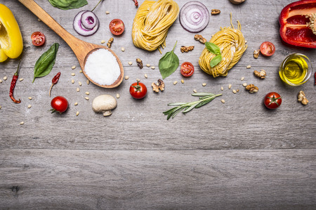 Healthy foods, cooking and vegetarian concept pasta with flour, vegetables, oil and herbs on wooden rustic background top view border, place for textの写真素材