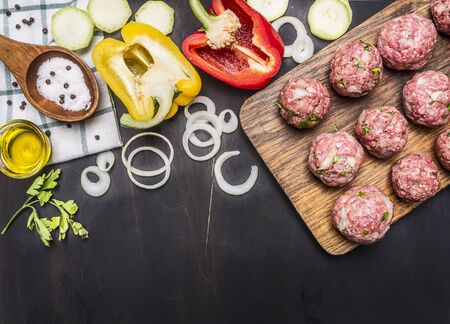 raw meat balls with herbs and onions on a cutting board with bell peppers, butter,  on wooden rustic background top viewの写真素材