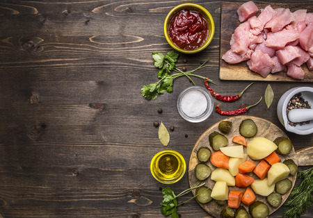 sliced raw turkey with potatoes, carrots and pickles, ingredients for stew border, place for text on wooden rustic background top view close upの写真素材