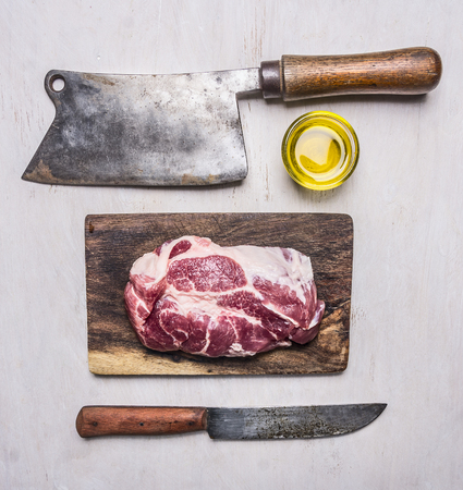 pork steak for grilling on a vintage cutting board with a meat cleaver on a wooden rustic background top view close upの写真素材