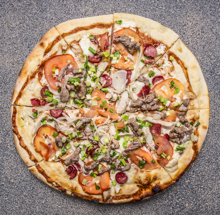 homemade pizza with bacon, tomatoes and cheese on rustic background top view close upの写真素材