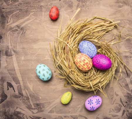 colorful, painted decorative Easter eggs in the nest on wooden rustic background top view close upの写真素材
