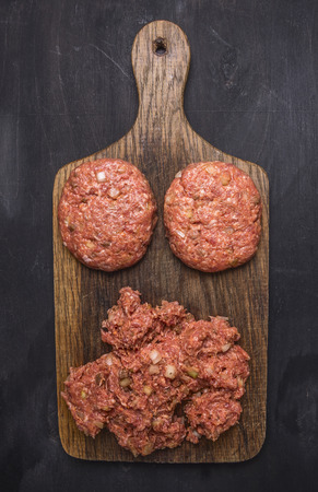 two cutlets for burgers with minced meat on a cutting board, on wooden rustic background top view close upの写真素材