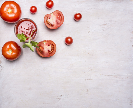 Fresh tomato juice in a glass with a straw, spread out around the sliced ??tomatoes on a wooden rustic background top view close upの写真素材