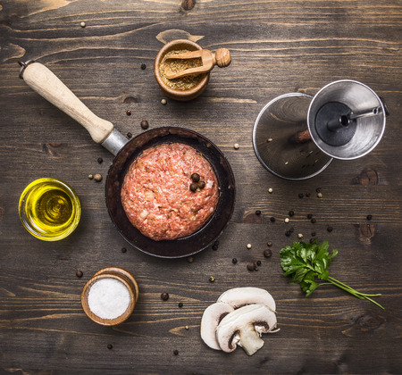 raw cutlet burger for a small frying pan, seasoning, butter, mushrooms, parsley on wooden rustic background top view close upの写真素材