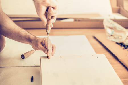 man assembles wardrobe, twists the screws in the slots, furniture assemblyの写真素材
