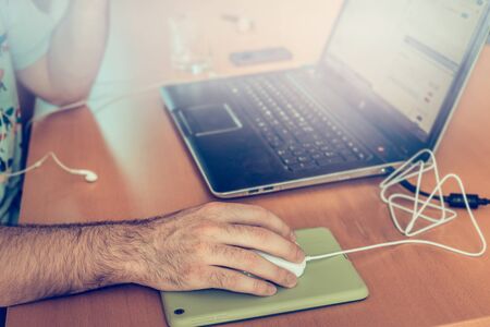 man working on a computer at home, at the table, in the rays of sunlight, blurred backgroundの写真素材