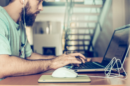 man with a beard is working at the computer, on the background of two floors of apartmentsの写真素材
