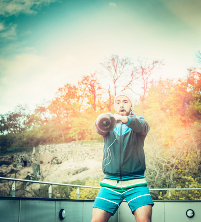 young man training with weights on the terrace of the house of the forest and sunset sky backgroundの写真素材