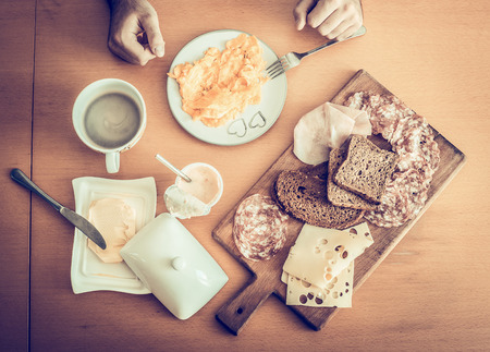 healthy breakfast, scrambled eggs, black coffee, sandwiches with salami and cheese , on a wooden table, top viewの写真素材