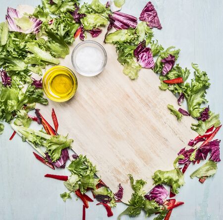 various types of lettuce lined frame around a cutting board, oil and salt, place for textの写真素材