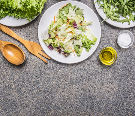 Ingredients for cooking vegetarian food, different varieties of lettuce, lined frame with wooden cutlery, spices and oil place for textの写真素材