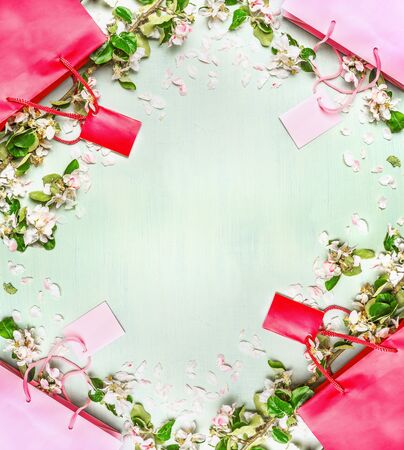 Red and pink shopping bags with summer or vessennimi flowers and leaves on a light mint background, top view, frame Spring or summer sale and shopping conceptの写真素材