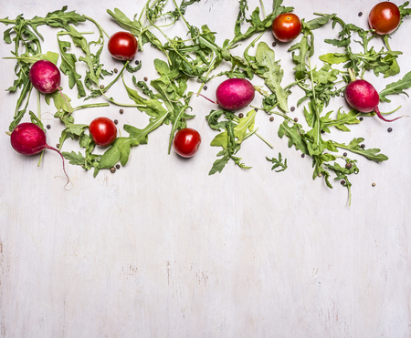 Ingredients for cooking vegetarian lettuce, radishes, cherry tomatoes, arugula laid out on a white wooden rustic background, place for textの写真素材