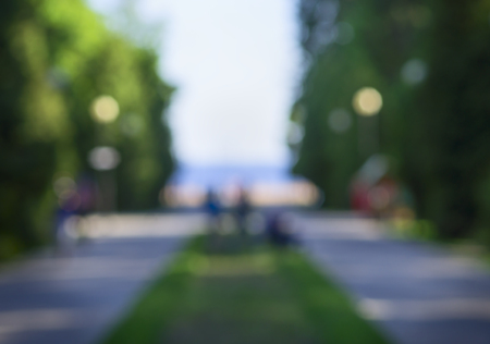 blurred landscape, sunny road to the beach through the park with trees and people silhouettes, background, bokehの写真素材